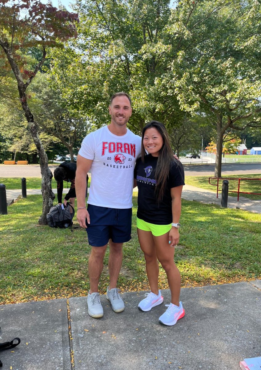 Coaches Arm-in-Arm: Coaches Barrett and Hair smiling in the new cross country community. Photo by Jasmine Phung, September 13, 2024.