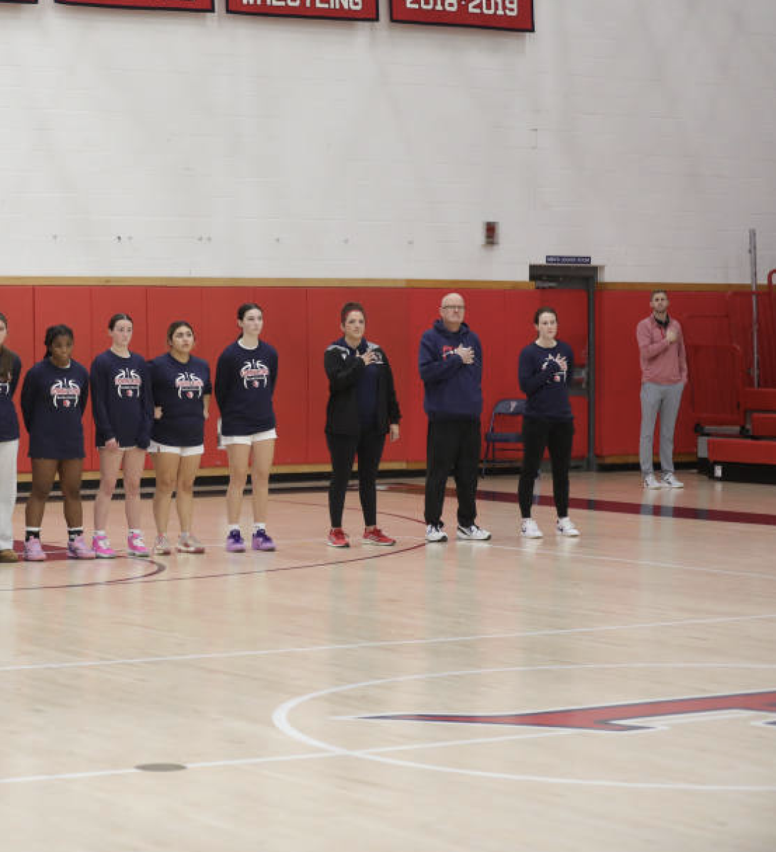 Coach Willey: Coach Willey standing for the pledge of allegiance with basketball coaches and players, January 7, 2025. 