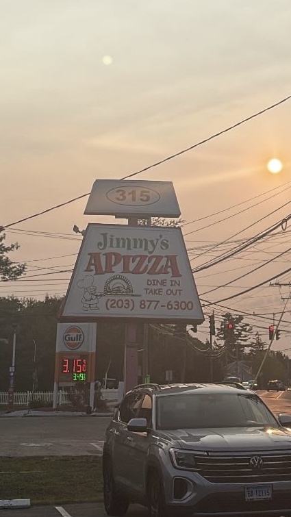 Dine In & Take Out: Jimmy’s Apizza sign glowing in the summer sunset, September 5, 2025. Photo courtesy: Devyn Hogan.