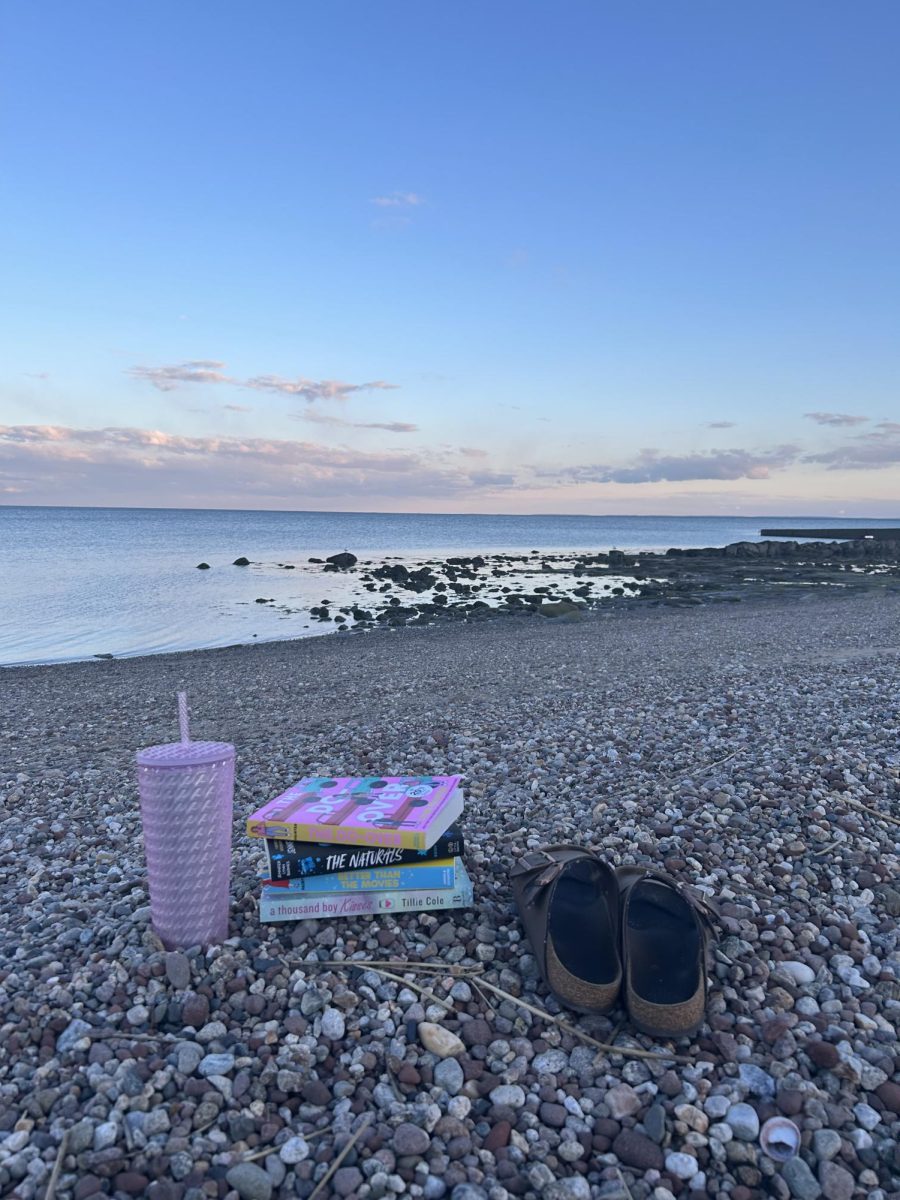 Birks ‘n Books: A stack of books lay on the sandy Woodmont beach, overlooking the ocean, while being flanked by a pair of Birkenstocks and a Starbucks water bottle, April 20, 2026. Photo courtesy: Leila Botonjic